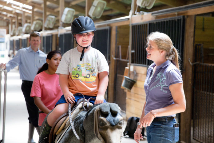 Clients do a variety of exercises on a “practice” horse before riding, such as getting on/off, holding the reins correctly, and doing leg exercises by posting.
